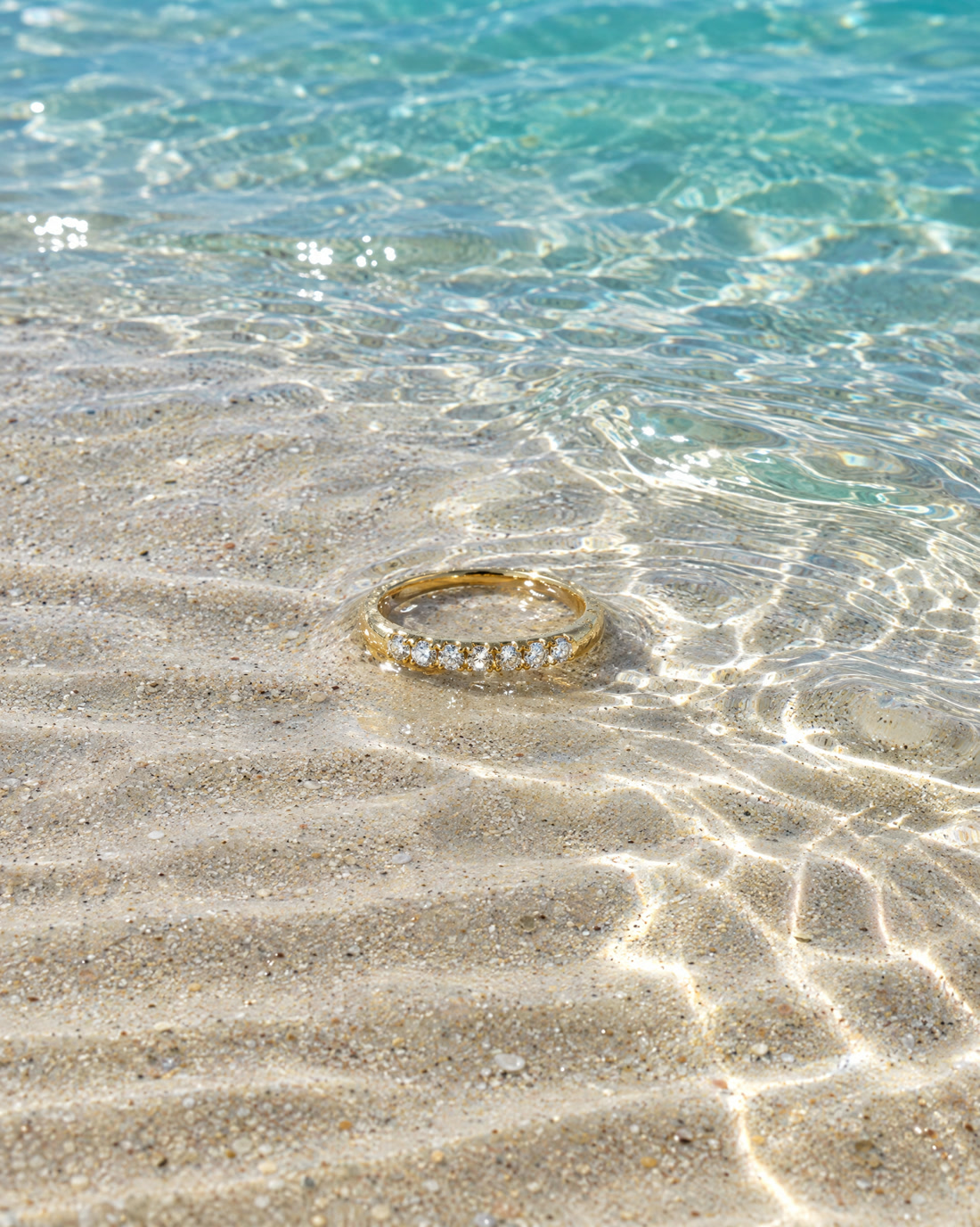The Ordinate Band, a yellow gold band set with nine small brilliants.
